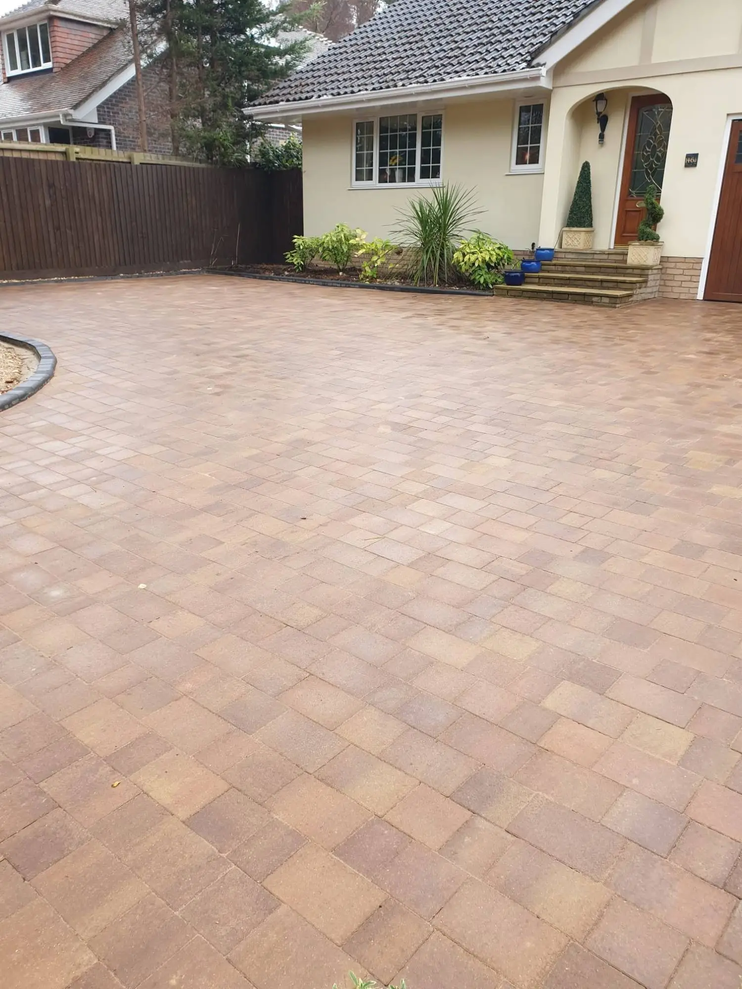 Brindle block-paved driveway in front of a bungalow with an arched porch