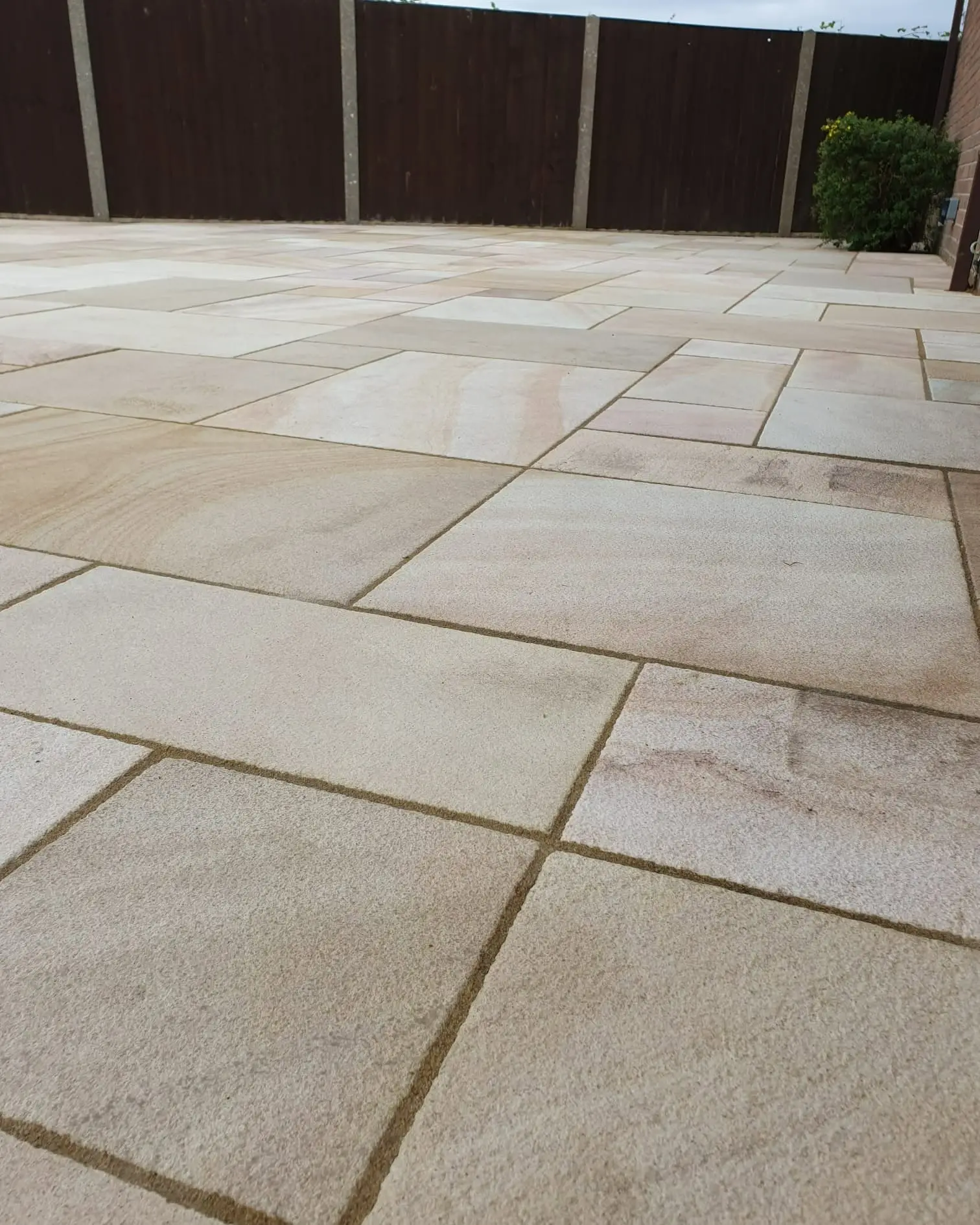 Close-up of newly laid sandstone paving slabs in front of a timber fence